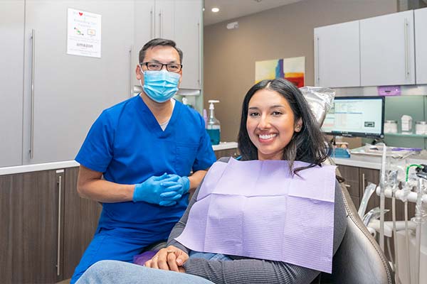 A woman smiling in dental chair with Dr. Le