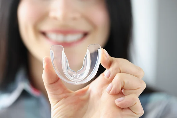 Close up of a simple mouth guard being held up by an excited woman Picasso Dental Care in Temecula, CA