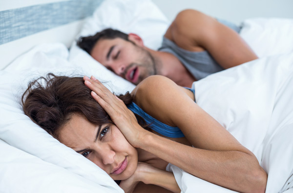 Woman covering ears while husband snores